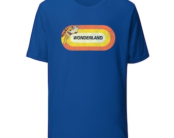 May include: Royal blue t-shirt featuring a retro-style graphic. The graphic includes the word "WONDERLAND" in a distressed font, set within an oval shape with orange, yellow, and white stripes. A vintage illustration is on the left side of the oval.