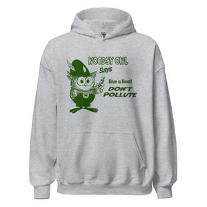May include: A light grey hooded sweatshirt with a green cartoon owl graphic and the text "WOODSY OWL Says Give a Hoot! DON'T POLLUTE." The owl is holding a small object. The sweatshirt has a front pocket and a drawstring hood.