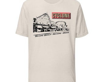 May include: Cream-colored t-shirt featuring a black and white illustration of a roller coaster and the text "CYCLONE" in a red box. Below the illustration is the text "REVERE BEACH - REVERE - MASS".