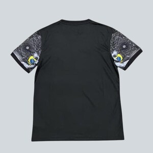 May include: Black short-sleeved t-shirt with patterned sleeves. The sleeves feature a detailed design in shades of gray, white, yellow, and blue. The shirt has a simple, classic crew neck design.