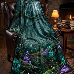 Puede incluir: Una manta verde oscuro con una escena de bosque que presenta hongos brillantes, una luna y un camino. La manta está sobre un sillón de cuero marrón, creando un ambiente acogedor.