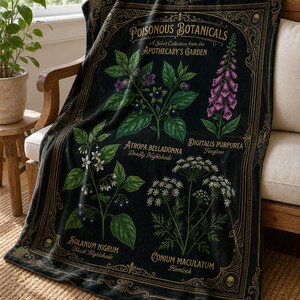 May include: A black throw blanket featuring a gold-toned ornate border and botanical illustrations of poisonous plants. The text reads Poisonous Botanicals, A Select Collection from the Apothecary's Garden, Atropa Belladonna, Digitalis Purpurea, Solanum Nigrum, and Conium Maculatum.