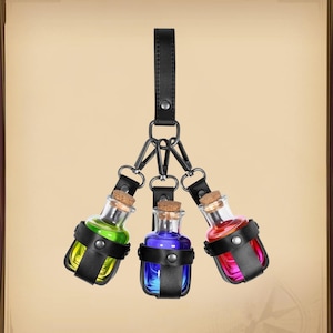 May include: A black leather keychain holds three small glass bottles with cork stoppers. Each bottle contains a different colored liquid: green, blue, and red. The bottles are secured in black leather holders.