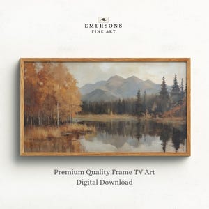 Op de afbeelding: Een landschapsschilderij in een rechthoekige houten lijst met een meer dat bergen en herfstbomen met oranje en bruin gebladerte weerspiegelt. De tekst EMERSONS FINE ART staat boven de lijst en Premium Quality Frame TV Art Digital Download staat eronder.