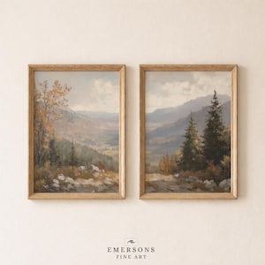 May include: Two vertical framed wall art prints featuring landscape paintings of mountain valleys with evergreen trees, rocky foregrounds, and autumn foliage in muted tones of brown, green, and grey. The text EMERSONS FINE ART appears below.