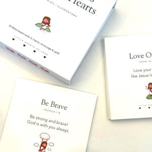 May include: A white box set of "Lunch Notes for Little Hearts" with the text "LITTLE KIDS / ELEMENTARY". The set includes 30 Bible-based cards with inspirational messages and illustrations. One card reads "Be Brave" with a Bible verse.
