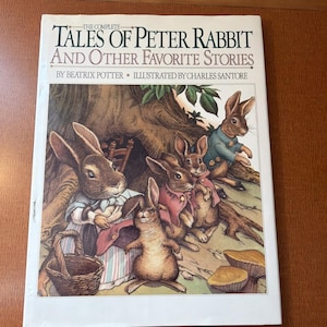 May include: A hardcover book titled "The Complete Tales of Peter Rabbit and Other Favorite Stories" by Beatrix Potter, illustrated by Charles Santore. The cover features a colorful illustration of several rabbits in a forest setting, with text at the top.