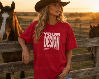 Puede incluir: Una camiseta roja de manga corta con el texto blanco "YOUR DESIGN" y "FORWARD NOTION MOCKUP SHOP" impreso en el frente, combinada con pantalones cortos de mezclilla azul y un sombrero de vaquero marrón, usada al aire libre cerca de caballos.