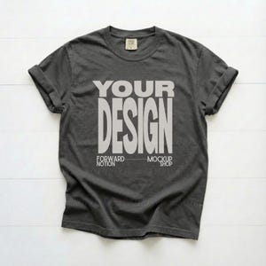 Op de afbeelding: Een antracietgrijs T-shirt met korte mouwen, een ronde hals en opgerolde mouwen. In het midden van het T-shirt staat de witte tekst "YOUR DESIGN" in een vet, schreefloos lettertype, met "FORWARD NOTION" en "MOCKUP SHOP" eronder gedrukt.