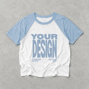 May include: A white short-sleeve raglan t-shirt with light blue sleeves and a round neckline. The center of the shirt features the text YOUR DESIGN in large light blue letters, with the smaller text FORWARD NOTION MOCKUP SHOP below it.