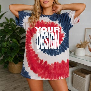 Può includere: Una t-shirt a maniche corte con un motivo tie-dye a spirale nei colori rosso, bianco e blu scuro. Al centro della maglietta è presente la scritta bianca in grassetto "YOUR DESIGN" disposta su due righe, con il testo più piccolo sotto.