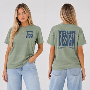 Puede incluir: Una camiseta de manga corta color verde salvia con texto azul oscuro. El frente muestra las palabras YOUR DESIGN en un diseño apilado. La parte posterior presenta el mismo texto en un tamaño de fuente mayor con FORWARD NOTION MOCKUP SHOP.
