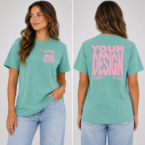 Puede incluir: Una camiseta de manga corta color verde azulado con texto rosa en el pecho izquierdo que dice "YOUR DESIGN" y una versión más grande del mismo texto rosa en la espalda, que también incluye el texto más pequeño "FORWARD NOTION MOCKUP SHOP".