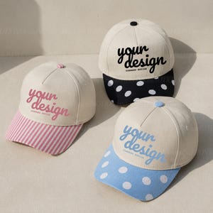 May include: Three baseball caps with off-white crowns and patterned brims. One cap has a pink striped brim and pink text, one has a black polka-dot brim and black text, and one has a blue polka-dot brim and blue text. All read your design.