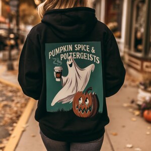 Puede incluir: Una sudadera negra con capucha que presenta un gráfico en la espalda con un fantasma blanco sosteniendo una taza de café y una calabaza tallada. El texto PUMPKIN SPICE & POLTERGEISTS aparece en blanco sobre un fondo verde oscuro.
