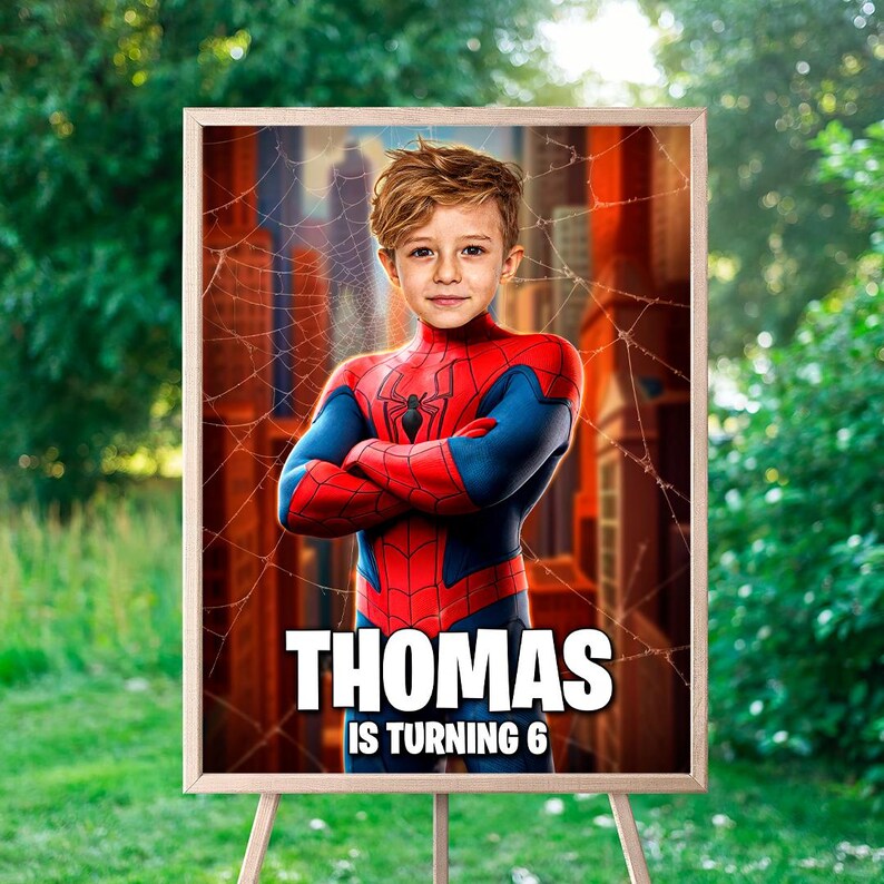 Peut inclure: Un portrait encadr&eacute; d'un jeune gar&ccedil;on d&eacute;guis&eacute; en Spider-Man, avec le nom "Thomas" et le texte "IS TURNING 6" en lettres blanches. L'arri&egrave;re-plan pr&eacute;sente une ville et une toile d'araign&eacute;e.