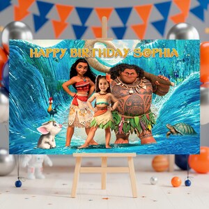 Op de afbeelding: Een kleurrijke verjaardagsbanner met personages uit de animatiefilm Moana, met de tekst "HAPPY BIRTHDAY SOPHIA". De banner wordt weergegeven op een houten ezel, met ballonnen en feestversieringen op de achtergrond.