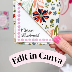 May include: A fabric corner bookmark featuring a cream background with a colorful floral pattern of red, blue, and green leaves. The bookmark displays a white insert with the text Corner Bookmark and a border of small pink flowers. The text Edit in Canva appears below.