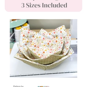 May include: Three bowl cozies in varying sizes, nested together. The cozies are square-shaped with floral and polka dot patterns. The text "Bowl Cozy Sewing Pattern 3 Sizes Included" is at the top. Finished dimensions are: Sm. 8", Med. 10", Lg. 12".