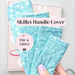 May include: Four quilted fabric skillet handle covers in varying lengths, featuring a light blue background with a small white floral pattern. The text Skillet Handle Cover and PDF & VIDEO are visible on the items, which are stitched with a diamond pattern.