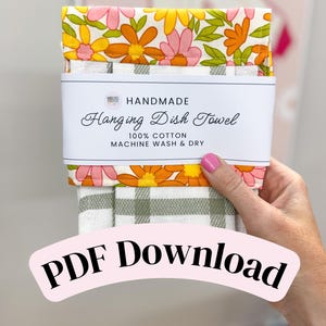 Puede incluir: Un paño de cocina colgante con un estampado floral de flores rosas, naranjas y amarillas sobre fondo blanco, combinado con una tela de cuadros verde salvia y blanca. Una banda de papel blanco dice HANDMADE Hanging Dish Towel 100% COTTON MACHINE WASH & DRY. El texto PDF Download aparece superpuesto en la parte inferior.
