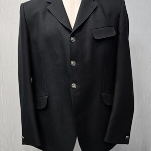 以下が含まれることがあります： 3つのシルバーボタンと2つのフロントポケットが付いた黒いブレザー。ブレザーはマネキンに展示されています。ブレザーはノッチドラペルとテーラードフィットです。袖口にはボタンが付いています。