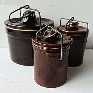 Puede incluir: Una taza de cerámica blanca con un asa negra y el texto "But First, Coffee" en negro, con una fuente de estilo manuscrito. La taza está sobre una superficie blanca.