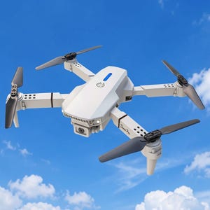 Puede incluir: Un dron cuadricóptero blanco con cuatro hélices negras, una lente de cámara central y una luz indicadora azul en la carcasa superior. El cuerpo muestra el texto Drone Pro en letras negras cerca de uno de los cuatro brazos y rotores.