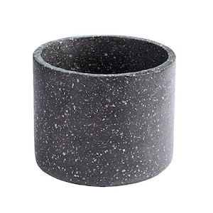 May include: A cylindrical, dark gray planter with a speckled pattern. The planter is made of a concrete-like material and has a smooth, rounded rim. The interior is hollow, suitable for holding plants or other decorative items.