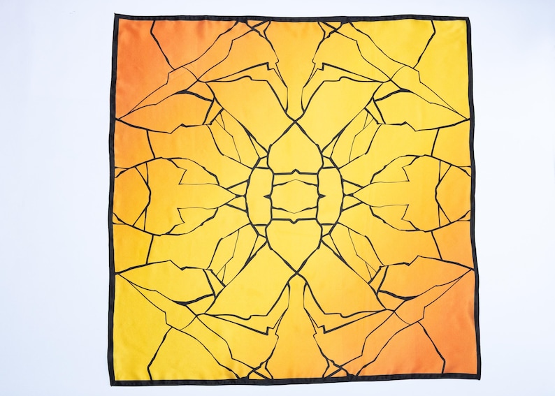 K&ouml;nnte beinhalten: Quadratisches Tuch mit einem lebendigen, abstrakten Design. Es zeigt einen Farbverlauf von Gelb und Orange mit einem schwarzen geometrischen Muster, das an zerbrochenes Glas erinnert. Ein schwarzer Rand umrahmt das Design.