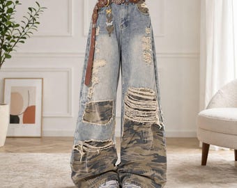 May include: Light blue denim wide-leg jeans with distressed details, camouflage patches, and a brown leather belt with decorative metal accents. The jeans have ripped sections and are worn with sneakers.