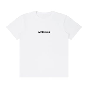Puede incluir: Una camiseta blanca con la palabra "overthinking" impresa en negro en el centro. La camiseta tiene cuello redondo y mangas cortas. La tela parece ser un material suave y ligero, ideal para el uso diario.