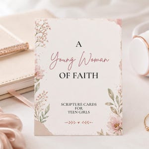 May include: A rectangular card with a cream background featuring pink floral illustrations and green leaves. The text reads A Young Woman OF FAITH SCRIPTURE CARDS FOR TEEN GIRLS. The design includes delicate sprigs and a small heart icon.