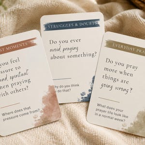 May include: Three white rectangular cards with text and watercolor accents. The cards are labeled "Honest Moments," "Struggles & Doubts," and "Everyday Prayer." Each card features a question and space for a response, with a neutral background.