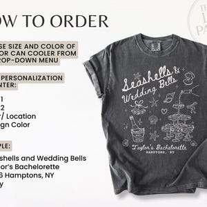 K&ouml;nnte beinhalten: Dunkelgraues T-Shirt mit wei&szlig;er Schrift und Illustrationen. Das Shirt zeigt die Worte "Seashells & Wedding Bells" und ein Design aus Sektgl&auml;sern, Muscheln und anderen Hochzeitsgrafiken. Der Text "Taylor's Bachelorette" ist ebenfalls sichtbar.
