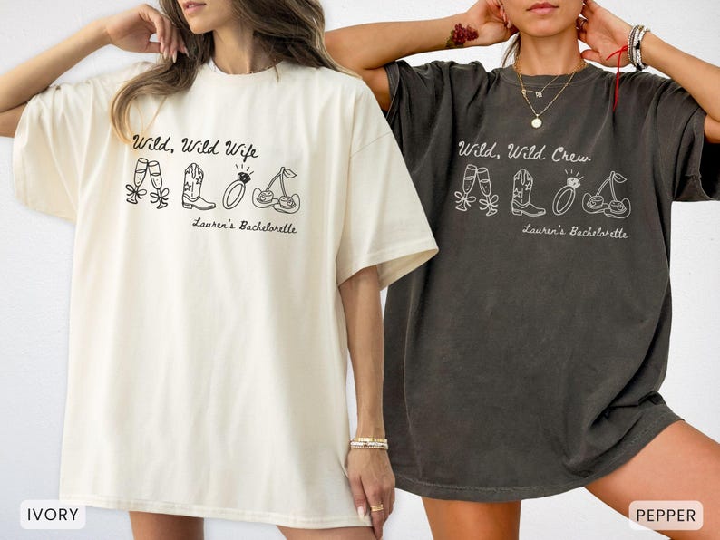 Puede incluir: Dos camisetas holgadas, una marfil y otra color pimienta, presentan los textos "Wild, Wild Wife" y "Wild, Wild Crew" con ilustraciones de copas de champ&aacute;n, botas de vaquero, un anillo y cerezas. Tambi&eacute;n se incluye el texto "Lauren's Bachelorette".