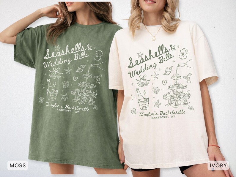 K&ouml;nnte beinhalten: Zwei &uuml;bergro&szlig;e T-Shirts, eines in Moosgr&uuml;n und eines in Elfenbein, mit einer wei&szlig;en Grafik. Die Grafik zeigt den Text "Seashells & Wedding Bells" mit Illustrationen von Champagner, Muscheln und Sektgl&auml;sern. Der Text "Taylor's Bachelorette, Hamptons, NY" ist ebenfalls enthalten.