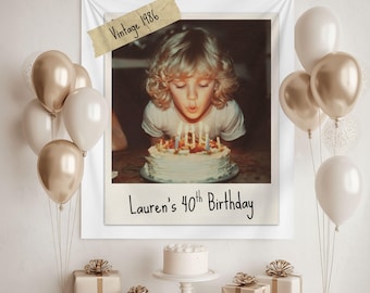 May include: A vintage-style birthday celebration scene. A framed photo shows a person blowing out candles on a cake. The photo is labeled "Vintage 1986" and "Lauren's 40th Birthday." Balloons in gold and white, gifts, and a small cake complete the festive decor.