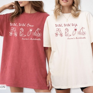 Puede incluir: Dos camisetas holgadas, una carmes&iacute; y otra marfil, con los textos "Wild, Wild Crew" y "Wild, Wild Wife" respectivamente. Cada camiseta presenta un dibujo lineal de copas de champ&aacute;n, una bota de vaquero, un anillo y cerezas. "Lauren's Bachelorette" est&aacute; impreso debajo.