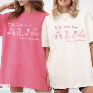 Puede incluir: Dos camisetas holgadas, una en rosa vibrante y otra en marfil, presentan los textos "Wild, Wild Crew" y "Wild, Wild Wife" con ilustraciones a juego. Los dise&ntilde;os incluyen copas de champ&aacute;n, botas, un anillo y cerezas, perfectas para una despedida de soltera.