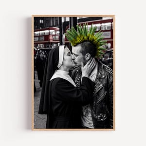 May include: A black and white photograph featuring a person in a black and white habit kissing a person with a bright green mohawk hairstyle wearing a black leather jacket with metal studs, set against a blurred urban background with a red bus.