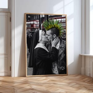 May include: A framed wall art print featuring a black and white photograph of a person in a nun's habit kissing a person with a bright green mohawk hairstyle wearing a black leather jacket with metal studs, set against a blurred city street.