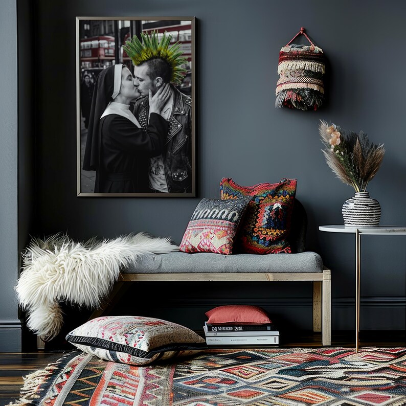 May include: A framed black and white photograph of a nun and a person with a green mohawk kissing, displayed above a wooden bench with a white faux fur throw, patterned pillows, a stack of books, and a woven wall hanging on a dark wall.