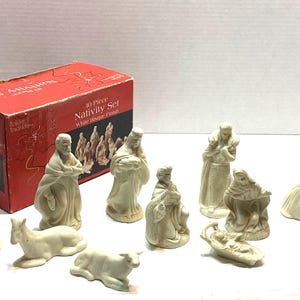 May include: A 10-piece nativity set with a white bisque finish, including figurines of people and animals. The set is packaged in a red box labeled 10 Piece Nativity Set White Bisque Finish, featuring a graphic of the figures on the front.