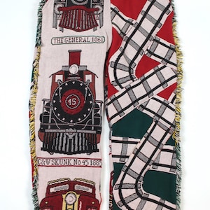 Può includere: Pantaloni a trama con illustrazioni di treni e motivi di binari. La gamba sinistra mostra immagini di treni con testo "THE GENERAL 1861", "C&W SKUNK No 45 1885" e "SANTA FE". La gamba destra ha un design di binari rosso, verde e bianco. I pantaloni hanno un cordoncino.