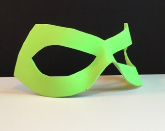 Può includere: Una maschera da supereroe verde brillante con un design semplice. La maschera ha un solo foro per l'occhio ed è realizzata in un materiale flessibile.