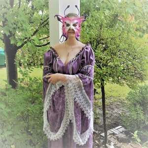May include: A woman wearing a purple dress with lace trim and a pink butterfly mask. The dress has a low neckline and the mask has intricate details.