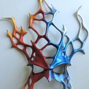 Pode incluir: Uma m&aacute;scara abstrata colorida feita de couro com um esquema de cores vermelho, laranja, amarelo, azul e branco. A m&aacute;scara tem um design geom&eacute;trico com um padr&atilde;o de teia de aranha.