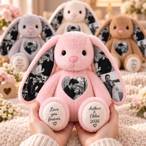 Può includere: Un coniglio di peluche rosa con stampe fotografiche in bianco e nero sulle lunghe orecchie e una toppa a forma di cuore sul petto. Le piante dei piedi bianche riportano il testo Love you forever e Arthur & Chloe 2026 con un piccolo cuore.