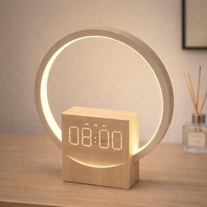 Puede incluir: Reloj despertador moderno de madera con pantalla digital que muestra las 08:00. Iluminado por una lámpara circular blanca. El reloj está sobre una superficie de madera. La lámpara tiene un diámetro de unos 20 cm.